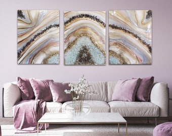 May include: Three abstract art panels featuring a geode design. The panels are a mix of white, brown, gold, and blue colours. The panels are arranged horizontally.