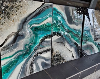 Puede incluir: Tres paneles de arte abstracto con un diseño marmoleado en azul verdoso, blanco y negro. Los paneles están decorados con pequeños detalles de brillo blanco y negro.