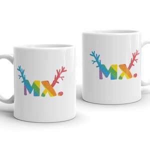 Könnte beinhalten: Zwei weiße Keramikbecher mit einem Regenbogen-Design, auf dem "MX." steht. Das Design beinhaltet Geweihe auf beiden Seiten der Buchstaben.