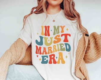 May include: White t-shirt with a colorful graphic that says "In My Just Married Era".
