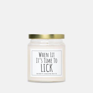 Puede incluir: Una vela en tarro de cristal transparente con tapa dorada. La etiqueta blanca tiene el texto "WHEN LIT IT'S TIME TO LICK". La vela est&aacute; vertida a mano y hecha con cera de soja mezclada.
