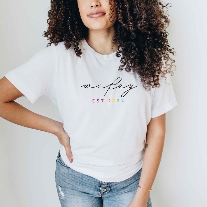 May include: White t-shirt with the text "wifey est 2022" in black script. The "est" is in rainbow colors.
