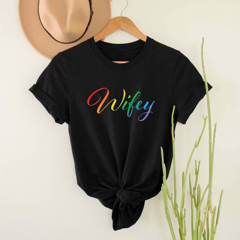 May include: Black t-shirt with the word "Wifey" written in rainbow colors.