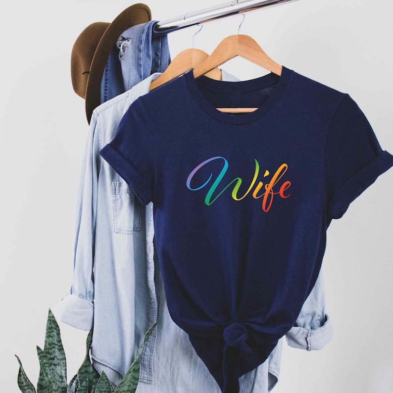 May include: A navy blue t-shirt with the word "Wife" written in rainbow colors.