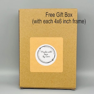 May include: A brown cardboard gift box with a sticker that reads "Made with love by Gem." The text "Free Gift Box (with each 4x6 inch frame)" is printed on the box. The box is on a gray background.