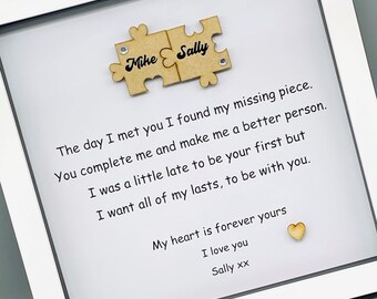 May include: A white frame with a white mat and a message inside. The message reads "The day I met you I found my missing piece. You complete me and make me a better person. I was a little late to be your first but I want all of my lasts, to be with you. My heart is forever yours I love you Sally xx". Two wooden puzzle pieces are attached to the top of the message. The puzzle pieces are labeled "Mike" and "Sally".