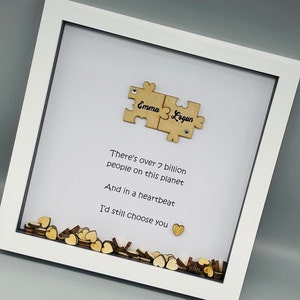 May include: White frame with a white background and a wooden puzzle piece with the names "Emma" and "Logan" on it. The frame also has a quote that reads "There's over 7 billion people on this planet And in a heartbeat I'd still choose you".
