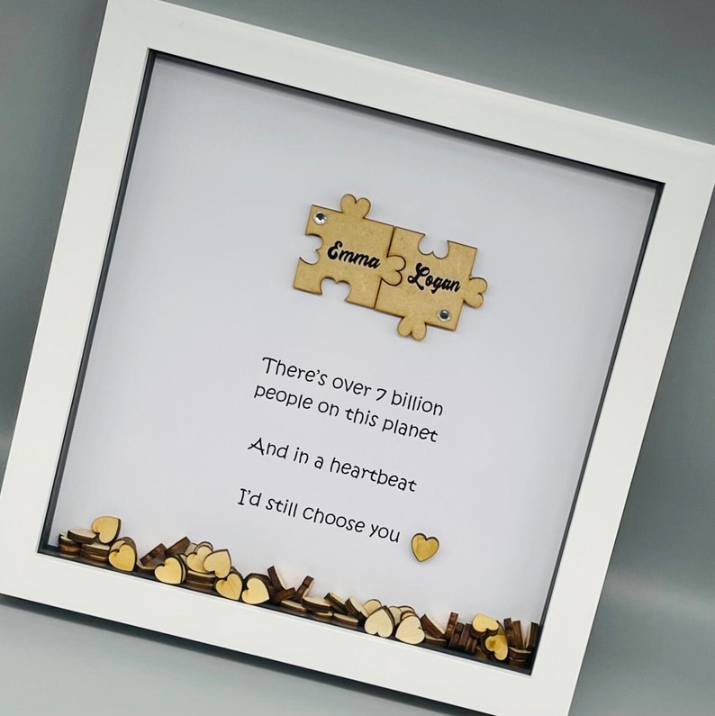 May include: White frame with a white background and a wooden puzzle piece with the names "Emma" and "Logan" on it. The frame also has a quote that reads "There's over 7 billion people on this planet And in a heartbeat I'd still choose you".