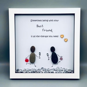 May include: Framed artwork featuring two pebble figures holding glasses of wine, with the text "Sometimes being with your Best friend is all the therapy you need" and two small wooden hearts.