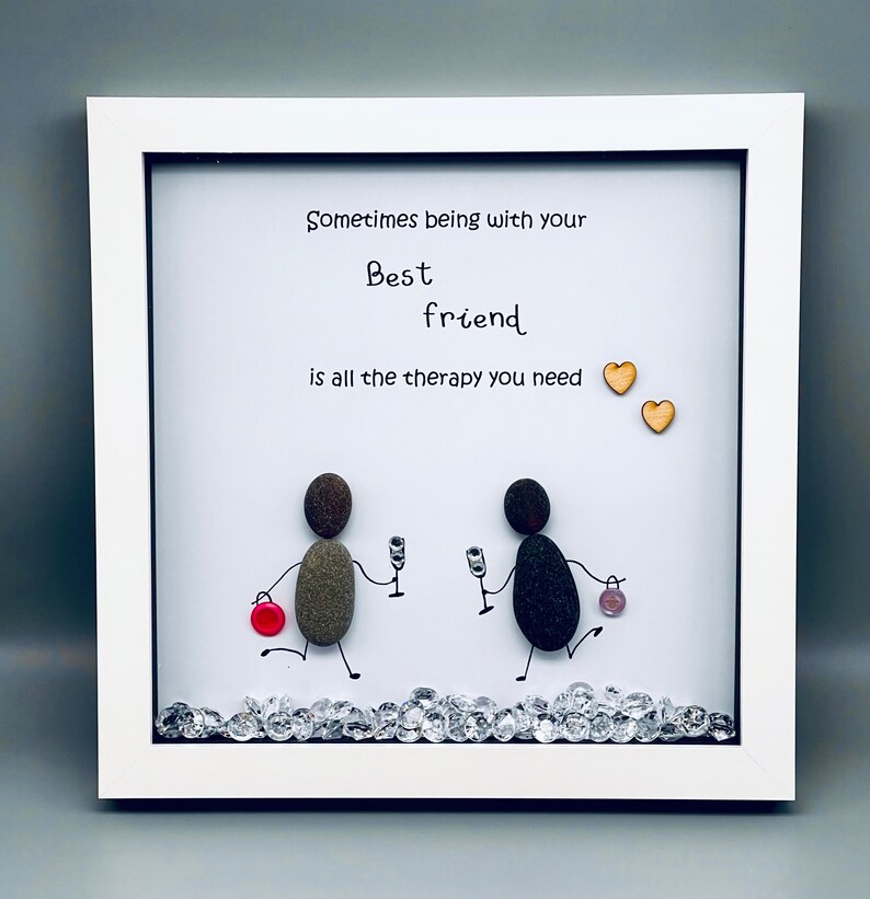 May include: Framed artwork featuring two pebble figures holding glasses of wine, with the text "Sometimes being with your Best friend is all the therapy you need" and two small wooden hearts.