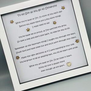 May include: A white frame with a handwritten message for a son going to university. The message includes words of encouragement and love. The frame is decorated with small gold stars and a wooden heart.