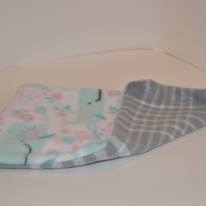 May include: A soft, reversible baby blanket with a floral pattern on one side and a gray and white striped pattern on the other side.