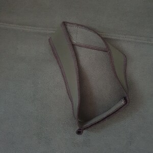 May include: A dark green fleece headband with a brown trim.