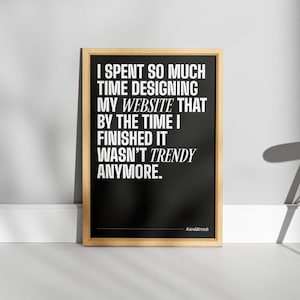 May include: Black and white typography poster with the text "I spent so much time designing my website that by the time I finished it wasn't trendy anymore." The poster has a wooden frame and the hashtag "#avoidtrends" is at the bottom.