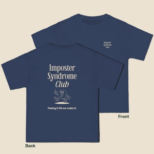 K&ouml;nnte beinhalten: Ein marineblaues T-Shirt mit einer wei&szlig;en Grafik auf der R&uuml;ckseite. Die Grafik zeigt eine Comicfigur mit dem Text "Imposter Syndrome Club" und "Faking it till we make it."