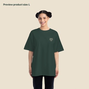K&ouml;nnte beinhalten: Ein dunkelgr&uuml;nes T-Shirt mit dem Aufdruck "Imposter Syndrome Club" auf der Vorderseite.
