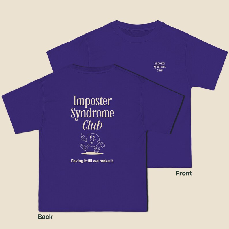 K&ouml;nnte beinhalten: Lilafarbenes T-Shirt mit dem Text "Imposter Syndrome Club" und einer Comicfigur auf der R&uuml;ckseite. Die Vorderseite des Shirts tr&auml;gt den Text "Imposter Syndrome Club" in kleinerer Schrift.