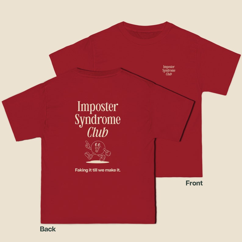 K&ouml;nnte beinhalten: Rotes T-Shirt mit einem wei&szlig;en Aufdruck auf der R&uuml;ckseite, der "Imposter Syndrome Club" mit einer Comicfigur und dem Text "Faking it till we make it." lautet. Die Vorderseite des Shirts hat einen kleinen wei&szlig;en Aufdruck mit der Aufschrift "Imposter Syndrome Club".