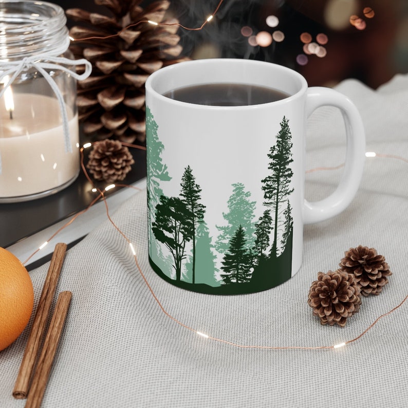 A Pine tree coffee mug in its natural habitat. The 11 Ounce capacity is ideal for thirst quenching with an ergonomic comfortable feel. Smooth Orca coating with a high quality vivid print.