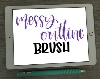 May include: A white tablet screen with the text "messy outline brush" in purple and black lettering. A green stylus is lying on a gray surface below the tablet.