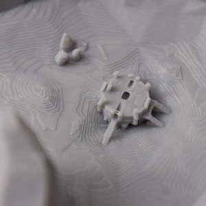 May include: A 3D printed model of a small building with a detailed design. The building is printed in a light gray color and has a textured surface.