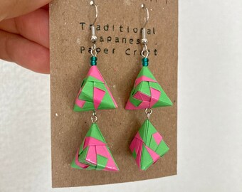 Könnte beinhalten: Origami-Ohrringe mit grünen und rosa geometrischen Formen. Die Ohrringe bestehen aus gefaltetem Papier und hängen an silberfarbenen Haken. Sie werden auf einer braunen Karte mit dem Wort "ORIGAMI" und dem Text "Traditional Japanese Paper Craft" präsentiert.