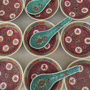 Het servies is versierd met het Mun Shou-patroon, symbool voor een lang leven. Set van 9 borden en 3 serveerlepels. In roze en gouden tinten. Magisch. Rond, 7,5 cm.
