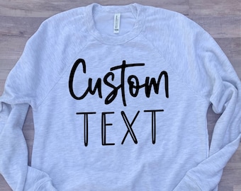 May include: A light gray sweatshirt with black text that says "Custom Text".