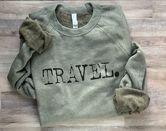 May include: A gray sweatshirt with the word "TRAVEL" printed in black on the front.