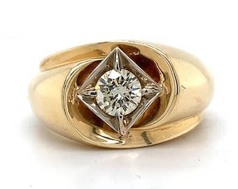 May include: A gold ring with a single round diamond set in a square frame. The ring has a thick band with a curved design.
