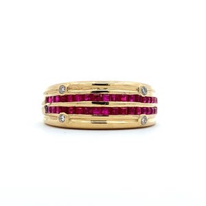 Könnte beinhalten: Ein goldener Ring mit drei Reihen quadratisch geschliffener, leuchtend roter Edelsteine. Der Ring ist mit vier kleinen, runden, klaren Edelsteinen verziert. Das Design ist symmetrisch, vor weißem Hintergrund.