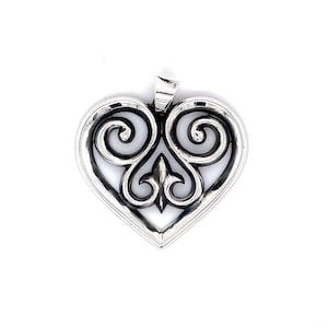 May include: A silver-toned heart-shaped pendant with an openwork design. The pendant features a central fleur-de-lis and swirling scrollwork. The bail is at the top for a chain. The pendant is on a white background.