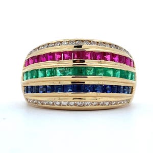 May include: A gold ring with three rows of gemstones. The top row features red rubies, the middle row has green emeralds, and the bottom row is blue sapphires. Small diamonds encircle the top and bottom of the ring.