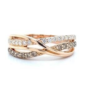 Könnte beinhalten: Roségoldener Ring mit gekreuzten Bändern. Das obere Band hat weiße Diamanten, das mittlere Band braune Diamanten und das untere Band weiße Diamanten. Der Ring ist vor einem weißen Hintergrund platziert.