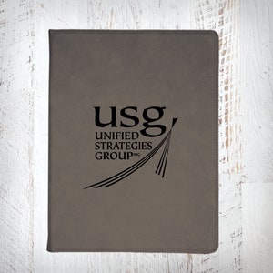 May include: A gray leather folder with the logo "USG Unified Strategies Group, Inc." printed in black.