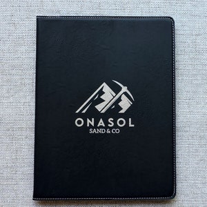 May include: Black leather folder with a silver embossed logo that says "ONASOL SAND & CO" and a graphic of a mountain with a pickaxe.