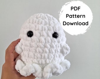 Könnte beinhalten: Ein weißer gehäkelter Geister-Amigurumi mit schwarzen Augen. Der Geist wird von einer Hand gehalten. Der Text "PDF Pattern Download" und "NO-SEW PATTERN" ist auf dem Bild zu sehen.