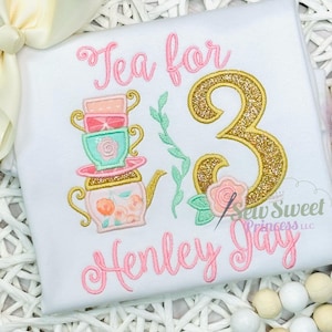 K&ouml;nnte beinhalten: Wei&szlig;es T-Shirt mit einem rosa Aufdruck "Tea for 3 Henley Jay". Das Design umfasst einen Stapel Teetassen, eine Teekanne, eine goldglitzernde Zahl 3 und florale Akzente. Der Text "Sew Sweet Princess LLC" ist ebenfalls sichtbar.