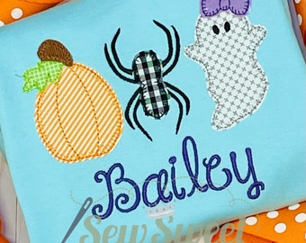 May include: Light blue Halloween-themed shirt with a pumpkin, spider, and ghost applique. The name "Bailey" is embroidered in purple script. The shirt has orange and white polka dot ribbons in the background.