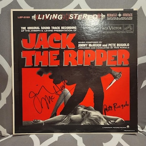 May include: Vintage vinyl record album cover for "Jack the Ripper." The cover has a red background with the title in large, bold letters. A shadowy figure with a knife is depicted above a woman. Includes signatures.