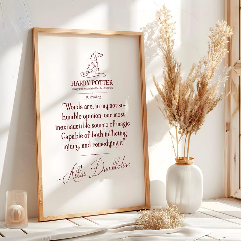 May include: A framed print with a quote from Albus Dumbledore from the Harry Potter series. The print is in a wooden frame and features the Harry Potter logo and author's name. A vase of dried flowers is next to the frame.