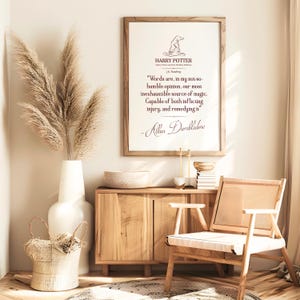 May include: A framed print featuring a quote from Harry Potter, in a light wood frame. The room includes a white vase with pampas grass, a wooden cabinet, a woven basket, and a wooden chair. The print features the Harry Potter logo and a quote by Albus Dumbledore.