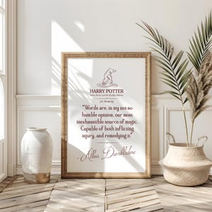 May include: A framed print with a quote from Harry Potter and the Deathly Hallows. The text, in a dark red font, is attributed to Albus Dumbledore. The frame is light brown, and the background is white. The image includes a Sorting Hat illustration.