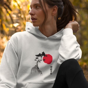 May include: White hoodie with a black and red Japanese-style design of a tree and a rising sun. The text on the hoodie reads "昇る太陽".