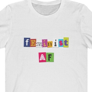 May include: White t-shirt with the text "feminist AF" in colorful, cut-out letters.
