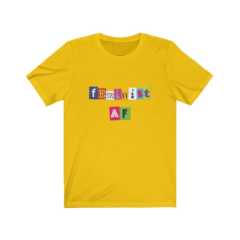 May include: Yellow t-shirt with the text "feminist AF" in colorful letters.