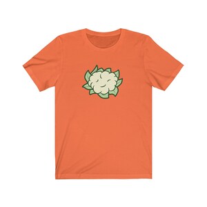 May include: Orange short-sleeved t-shirt with a cartoon image of a white cauliflower with green leaves.