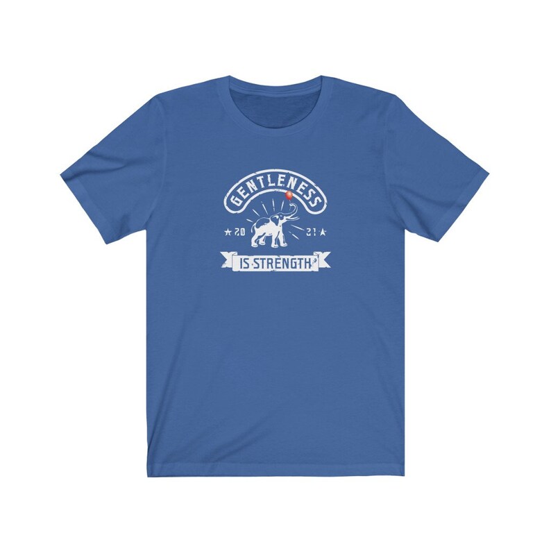 Puede incluir: Una camiseta azul con un gr&aacute;fico blanco. El gr&aacute;fico incluye un elefante, la palabra "GENTLENESS" y la frase "IS STRENGTH". El gr&aacute;fico tambi&eacute;n presenta los n&uacute;meros "20" y "21".