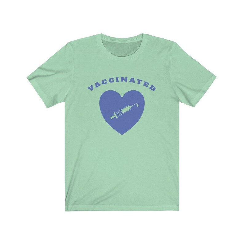 May include: A light green t-shirt with the text "VACCINATED" in blue letters. A blue heart with a syringe inside is below the text.