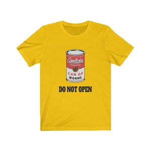 Puede incluir: Camiseta amarilla con un gr&aacute;fico de una lata roja etiquetada "Caecilians Condensed Can of Worms" con el texto "Do Not Open" en negro.